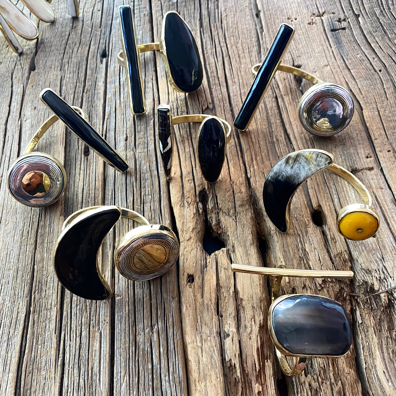 # Vintage Onyx and Gold-Filled Jewelry Collection

This collection of vintage brooches and pins features polished black onyx stones set in gold-filled or gold-tone metal settings, characteristic of mid-20th century costume jewelry. The pieces showcase various shapes including crescents, ovals, and geometric forms, with several displaying decorative metal bezels and ornamental details. Notable stones include amber, citrine, and dark blue or black cabochon stones, representing the glamorous aesthetic popular from the 1940s through 1960s.